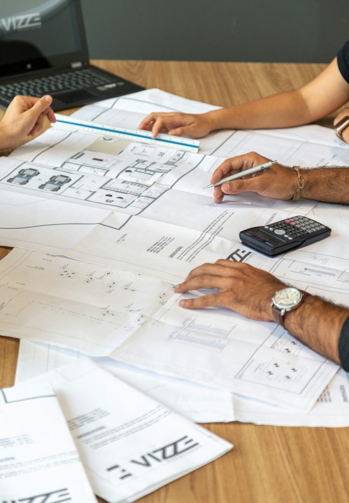 Hands reviewing construction blueprints with a calculator on a desk